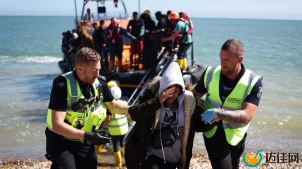 An interforce officer and a border force officer help a woman on the beach at Dungeness on the southeast coast of England, on August 16, 2023, after she disembarked from a Royal Natio<em></em>nal Lifeboat Institution (RNLI) lifeboat after being picked up at sea with other migrants while attempting to cross the English Channel from France. More than 100,000 migrants have crossed the Channel on small boats from France to southeast England since Britain began publicly recording the arrivals in 2018, official figures revealed on August 11, 2023. 