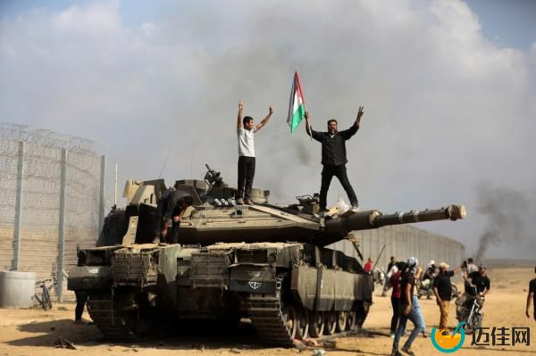 Palestinians wave their natio<em></em>nal flag and celebrate by a destroyed Israeli tank at the Gaza Strip fence east of Khan Younis southern Saturday, Oct. 7, 2023.