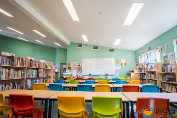Bright school classroom filled with colorful chairs all facing towards a whiteboard