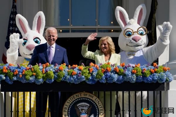 President Joe Biden and first lady Jill Biden standing on the Blue Room Balcony at the 2023 White House Easter Egg Roll, waving to people in bunny clothing.