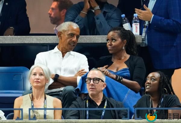 Barack and Michelle Obama sitting in stands talking. 