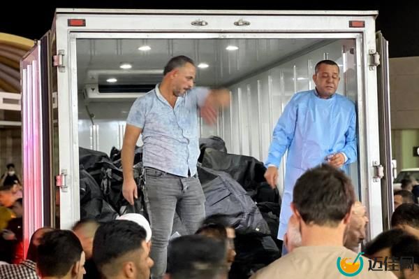 People gather around a truck carrying body bags after a fire broke out at a wedding hall.