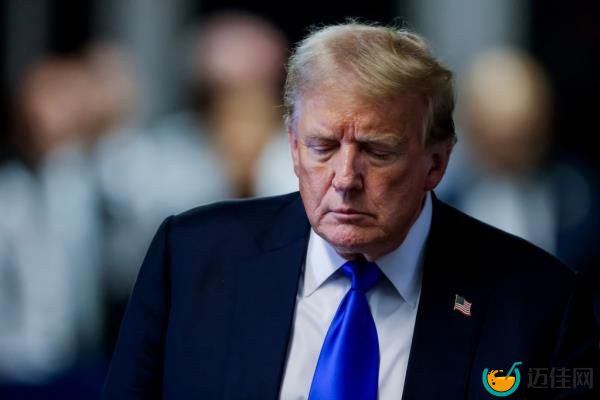 Do<em></em>nald Trump in a dark suit with a white shirt and blue tie looking downward