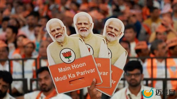 A supporter of the Bharatiya Janata Party (BJP) walks past a poster of Prime Minister Narendra Modi at its party