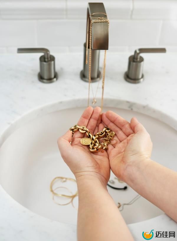 person washing hands with jewelry in the bathroom