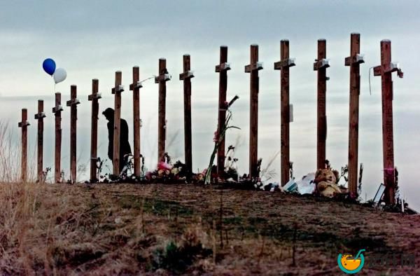 A woman stands among crosses posted on a hill above Columbine High School in Littleton, Colo., in remembrance of the people who died during a school shooting on April 20, 1999. 
