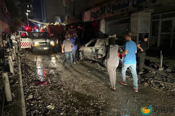 People walk near the building that was hit by an Israeli airstrike in the southern suburbs of Beirut, Lebanon.