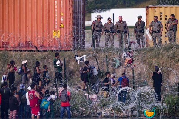 Texas Department of Public Safety officers observe migrants from behind co<em></em>ncertina after a group of migrants crossed the Rio Grande River on July 20, 2023.